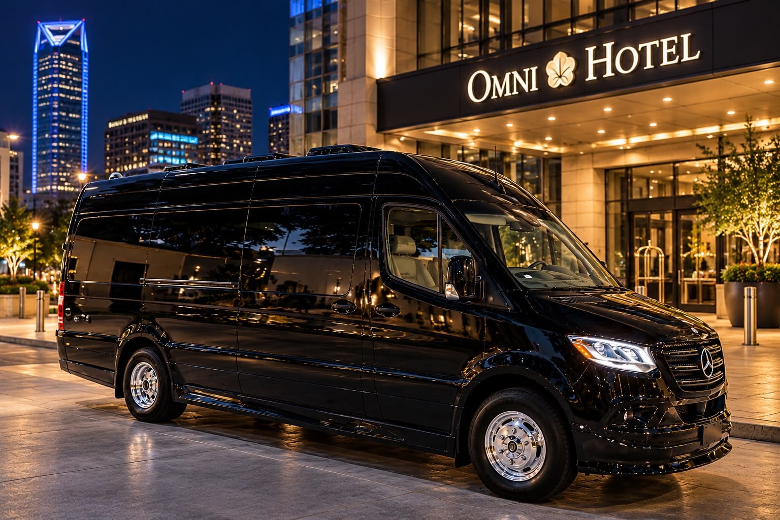 The Regent — black Mercedes-Benz Sprinter parked outside the Omni Hotel at night, downtown Oklahoma City skyline behind, Excalibur Executive